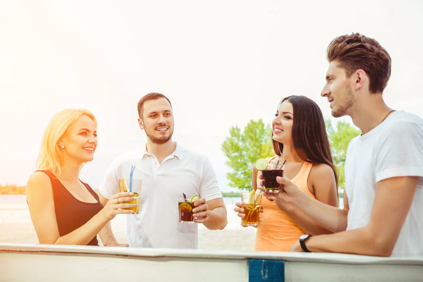 Друзі розважаються в барі на відкритому повітрі, п'ють коктейлі
. - Фото, зображення