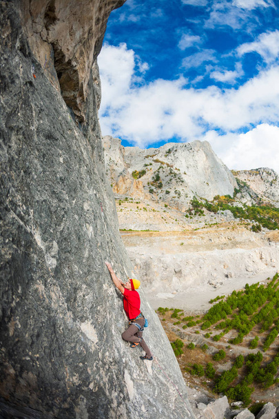 Bir kayanın üzerinde şapkalı bir dağcı. - Fotoğraf, Görsel