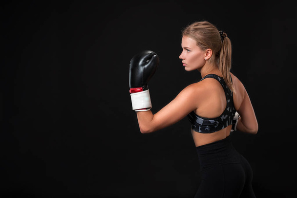 Beautiful female athlete in boxing gloves, in the studio on a black background. - Photo, image