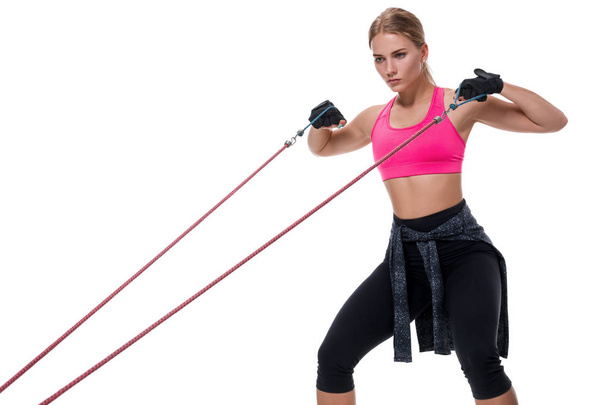 Strong woman using a resistance band in her exercise routine. Young woman performs fitness exercises on white background. - Valokuva, kuva