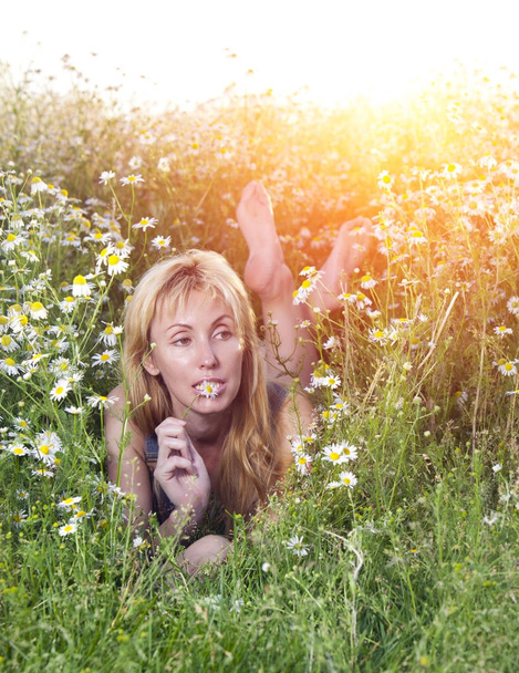 The beautiful happy young woman lies in the field of camomile - Photo, Image