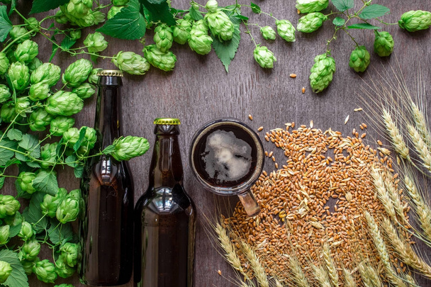 Fles en glas bier met tarwe en hop als Brewing ingrediënten in bovenste gedeelte voor weergave en kopie ruimte - Foto, afbeelding