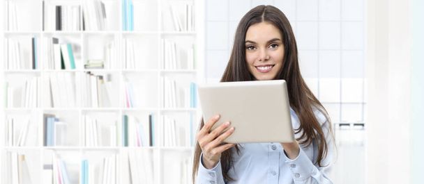 femme souriante avec tablette numérique sur fond de bibliothèque
 - Photo, image