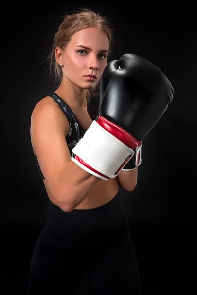schöne Athletin in Boxhandschuhen, im Studio vor schwarzem Hintergrund. Fokus auf den Handschuh - Foto, Bild