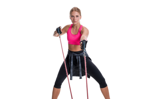 Η ισχυρή γυναίκα χρησιμοποιώντας μια μπάντα αντίσταση στη ρουτίνα άσκησης. Νεαρή γυναίκα εκτελεί ασκήσεις γυμναστικής σε λευκό φόντο. - Φωτογραφία, εικόνα