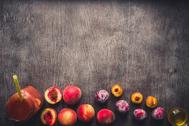 Perzik en pruimen Vruchtensmoothie in glazen fles en rietjes op houten tafel. Gezonde levensstijl. Toned - Foto, afbeelding