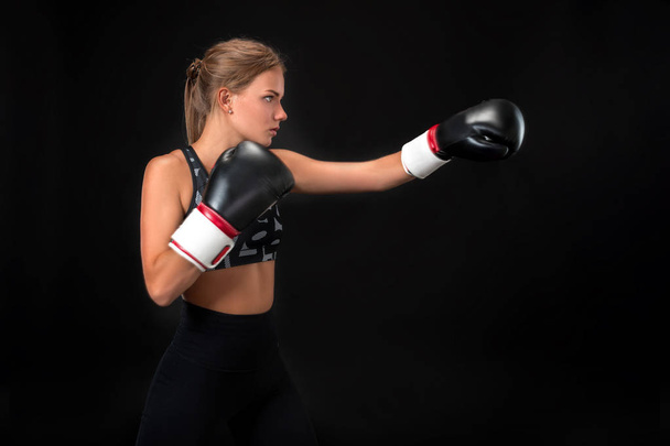Piękne kobiece kobieta lekkoatletka w Rękawice bokserskie, w studio na czarnym tle. - Zdjęcie, obraz