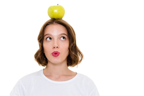 Thinking pretty caucasian woman holding apple on head - Foto, Bild