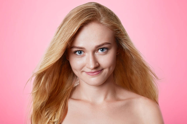 Portrait of confident beautiful woman with long luxurious hair being naked, poses and photographed on magazine cover, models against pink background. Headshot of attractive female has happy look - Photo, image