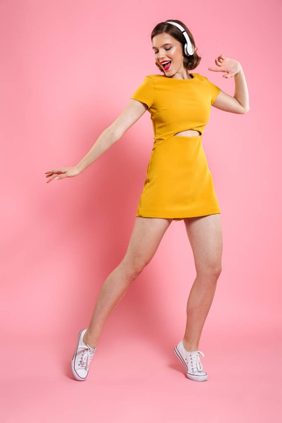 Excited happy young lady in yellow dress dancing - Photo, image