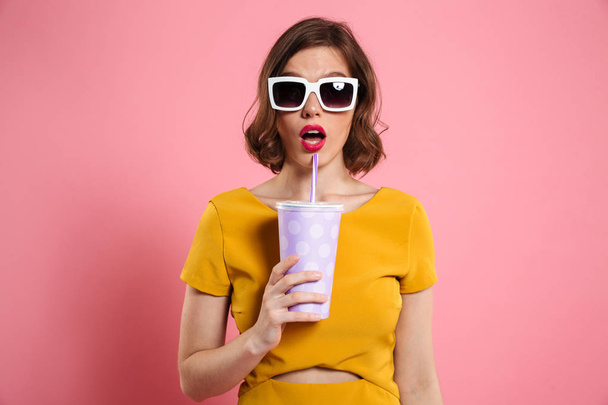 Portrait of a surprised girl in sunglasses holding cup - Foto, Imagem