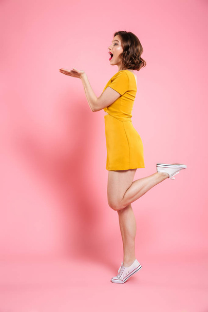 Full length portrait of playful attractive woman in yellow dress - 写真・画像