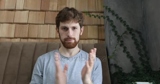 Red-haired guy clapping on a gray wall background - Video, Çekim