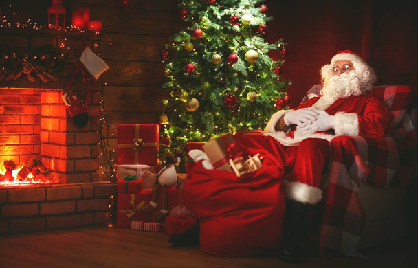 Merry Christmas! santa claus near the fireplace and tree with gi - Zdjęcie, obraz