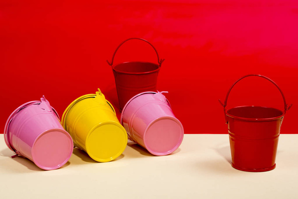 Ροζ, κόκκινο και κίτρινο κουβάδες σε έγχρωμο φόντο - Φωτογραφία, εικόνα