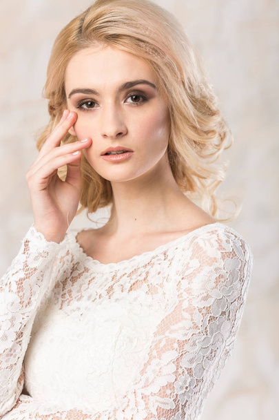 fashionable white gown, beautiful blonde model, bride hairstyle and makeup concept - young romantic lady in wedding festive dress standing indoors on light background, pretty woman posing - Foto, immagini