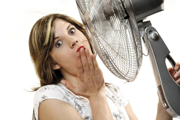Young woman cooling off in front of a fan, isolated on white background - Photo, image