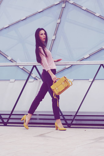 Hezká mladá model představuje v džínách a košili s žlutá kabelka. - Fotografie, Obrázek
