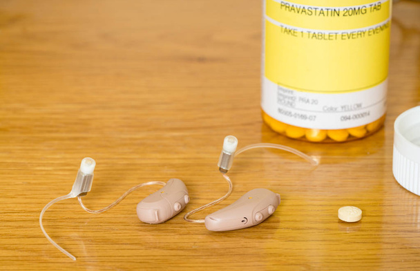 Close-up de um par de pequenos aparelhos auditivos modernos com medicamentos prescritos
 - Foto, Imagem