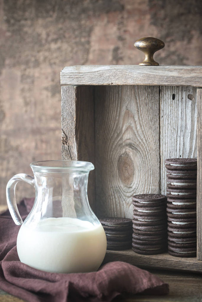 Schokoladenkekse mit cremiger Füllung mit Milchkrug - Foto, Bild