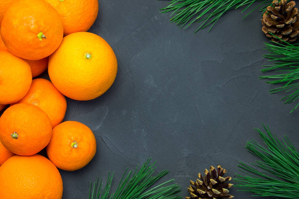 Orange and tangerine with branch christmas tree and cone on black concrete background - 写真・画像