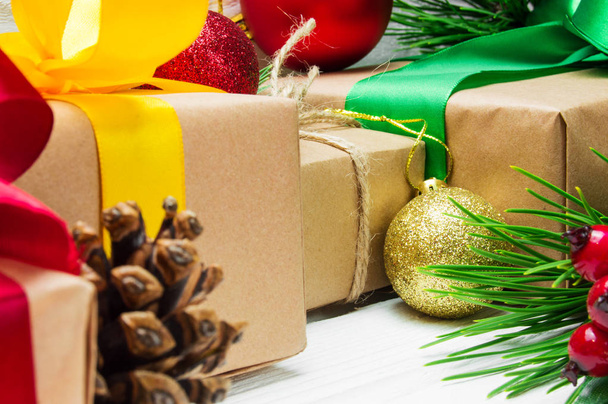 De doos van de gift van Kerstmis met tak en boog kerstboom van lint, bal speelgoed en kegel op witte houten vintage achtergrond - Foto, afbeelding