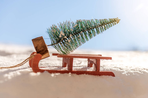 Trineo rojo llevando un pequeño árbol de Navidad
 - Foto, Imagen