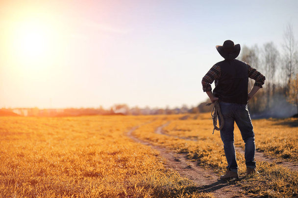 A man cowboy hat and a loso in the field. American farmer in a f - Fotoğraf, Görsel