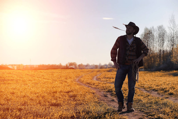 ein Mann Cowboyhut und ein Loser auf dem Feld. amerikanischer Bauer in einem f - Foto, Bild