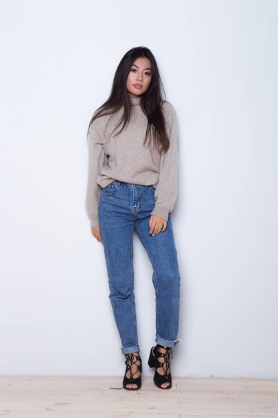 Moda posando hermosa chica asiática en el uso de moda. Ropa casual en jeans, zapatos de tacón alto y más dulces
 - Foto, imagen