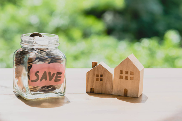 Glas mit Münzen Holzhaus. Geld für Hauskauf sparen - Foto, Bild