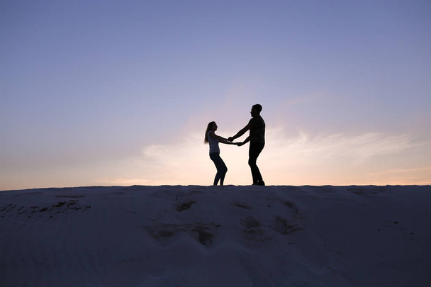 Lovers run towards each other and swirl on sandy hill in desert - Фото, изображение