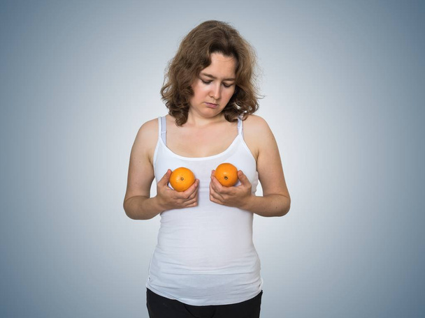 Genç üzücü ve tatminsiz kadın iki mandalina han içinde tutuyor - Fotoğraf, Görsel