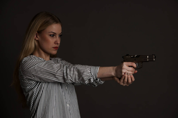 young dangerous blond woman with a gun - Foto, Imagen