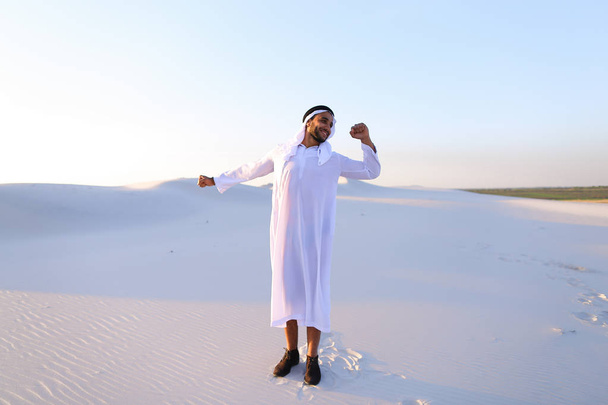 Cara muçulmano feliz caminha através de extensões de deserto e descansa com
 - Foto, Imagem