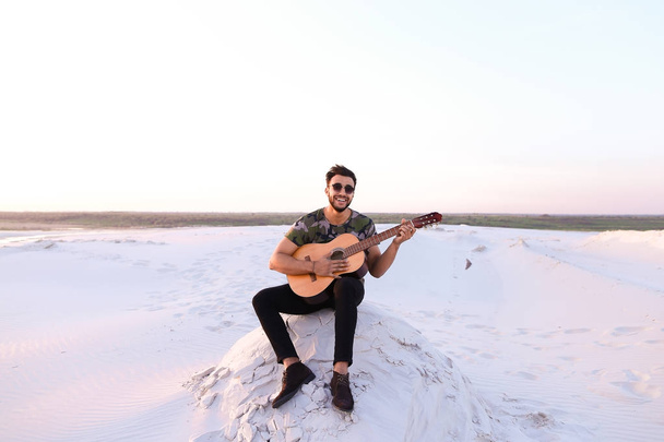 Mignon jeune arabe masculin aime le son de la guitare, assis sur la colline dans
 - Photo, image