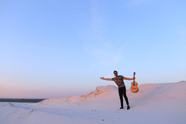 Arab guy goes inspired by beauty of desert and plays guitar stri - Photo, Image