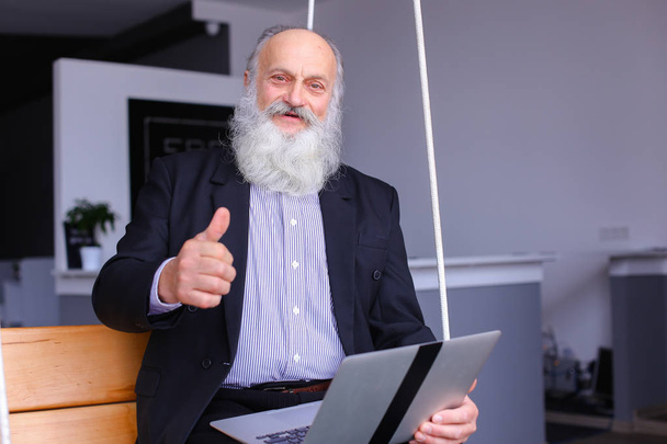 Old retired man uses laptop and communicates with colleagues beh - Foto, Imagem