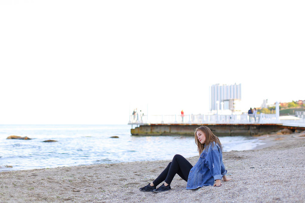 Hermosa joven mujer se relaja sentada en la playa y disfruta de la vista o
 - Foto, imagen