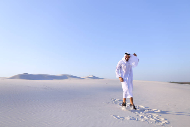 Hombre árabe feliz camina en medio del desierto blanco y disfruta de la vida o
 - Foto, imagen
