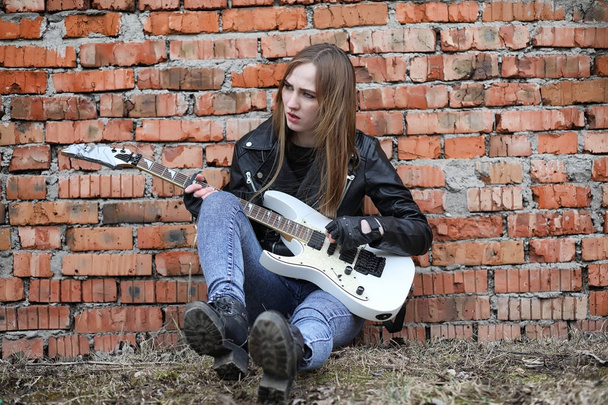 Рок-музыкантка в кожаной куртке с гитарой
 - Фото, изображение