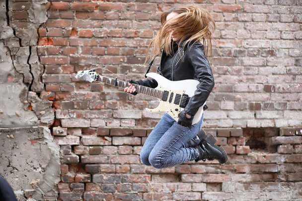 ein Rockmusikermädchen in Lederjacke mit Gitarre - Foto, Bild