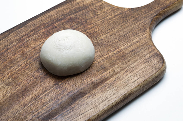 Pastel de arroz glutinoso sobre tabla de cortar madera; fondo blanco
 - Foto, imagen