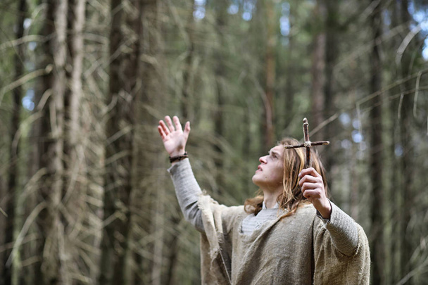 ein Mann in Soutane verbringt ein Ritual in einem dunklen Wald - Foto, Bild