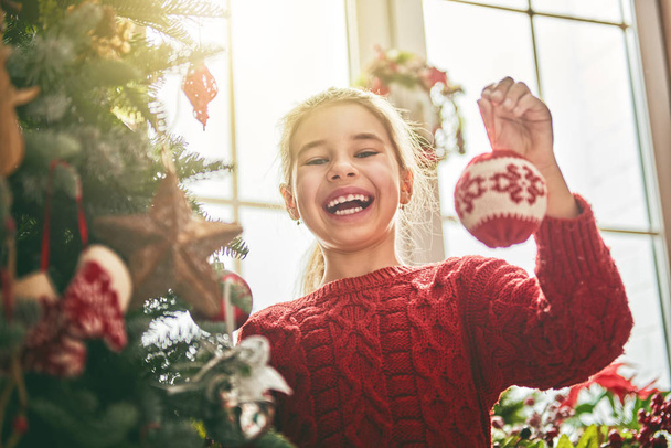 girl is decorating Christmas tree - Фото, зображення