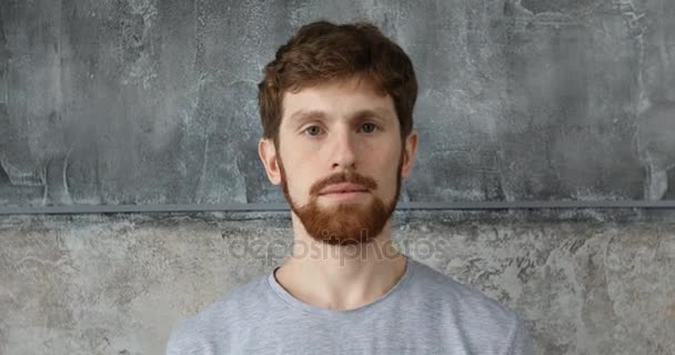 Red-haired bearded guy on a gray background - Footage, Video
