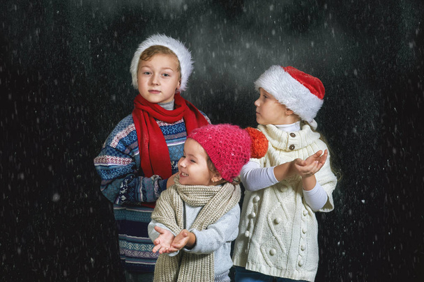 Niños jugando con copos de nieve sobre un fondo oscuro
 - Foto, Imagen