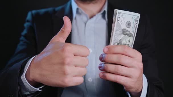Um homem de jaqueta preta e camisa branca segurando dinheiro
 - Filmagem, Vídeo