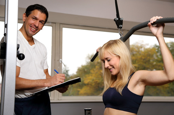 Attractive blonde woman and her trainer in a gym - Photo, Image