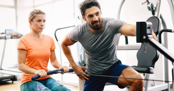 Personal trainer assisting woman lose weight in gym - Fotó, kép